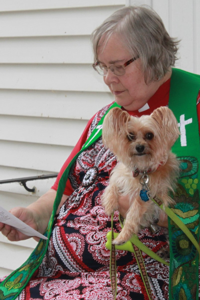 woman priest holding dog outside church